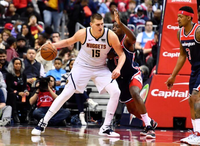 Nikola Jokic dribbles as Thomas Bryant defends
